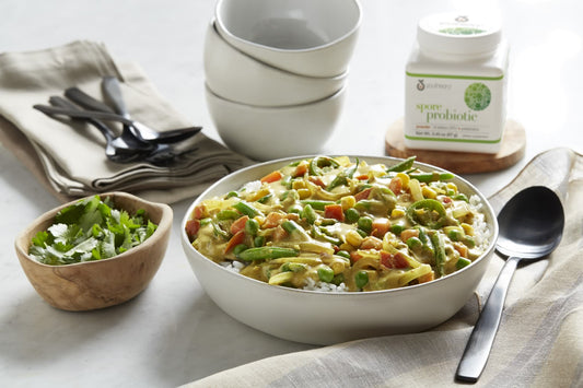 Spore Probiotic powder bottle next to Veggie Korma