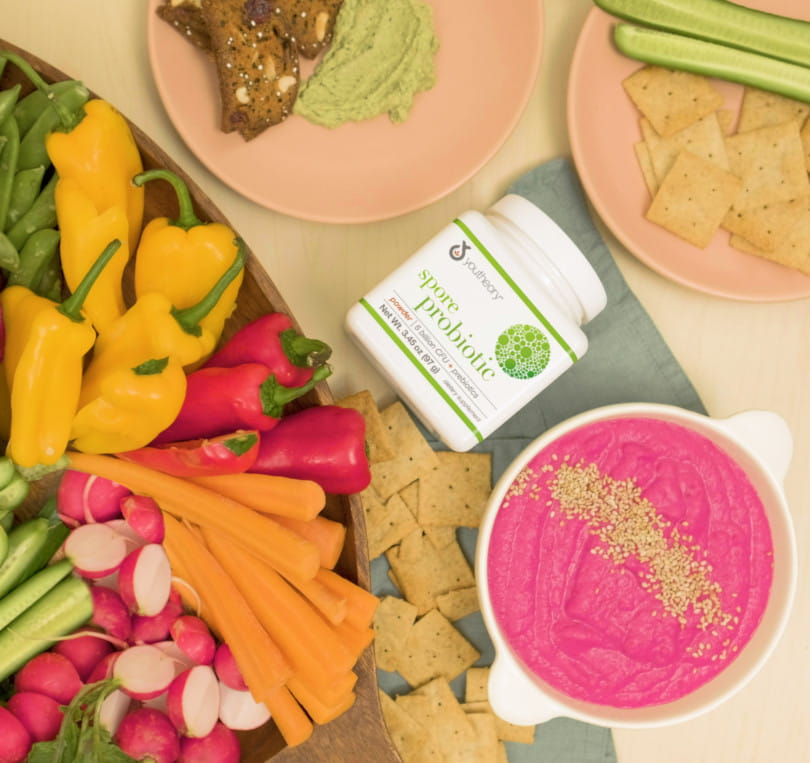 Spore Probiotic powder bottle next to Beet and White Bean Hummus