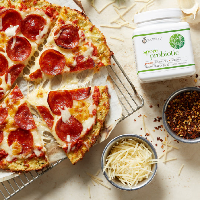 Spore Probiotic powder bottle next to cauliflower pizza