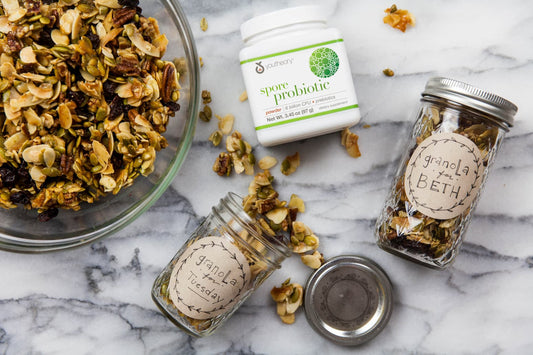 Spore Probiotic powder bottle next to Paleo Cherry Vanilla Granola