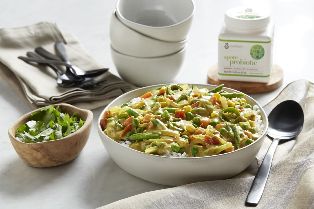 Spore Probiotic powder bottle next to Veggie Korma